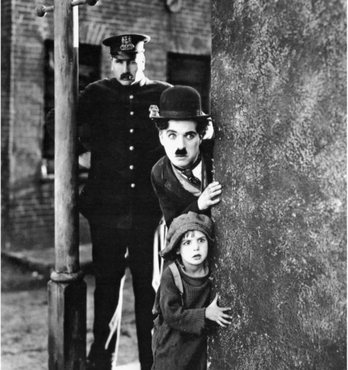 Charlie Chaplin standing with a young child and the police behind him