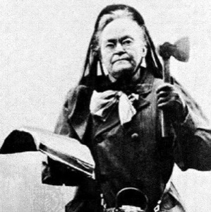 Black and white photo of woman dressed in black holding a hatchet in left hand and book in right
