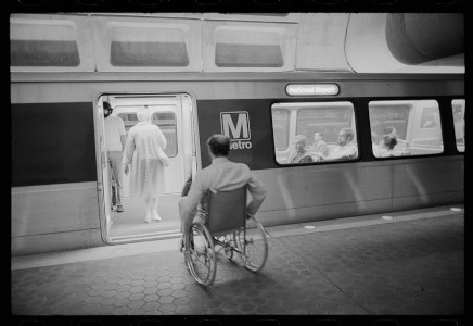 Photo shows a man using a wheelchair poised to enter an accessible subway car in Washington DC, mid 1970s.